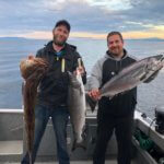 2 guys on boat with catch.