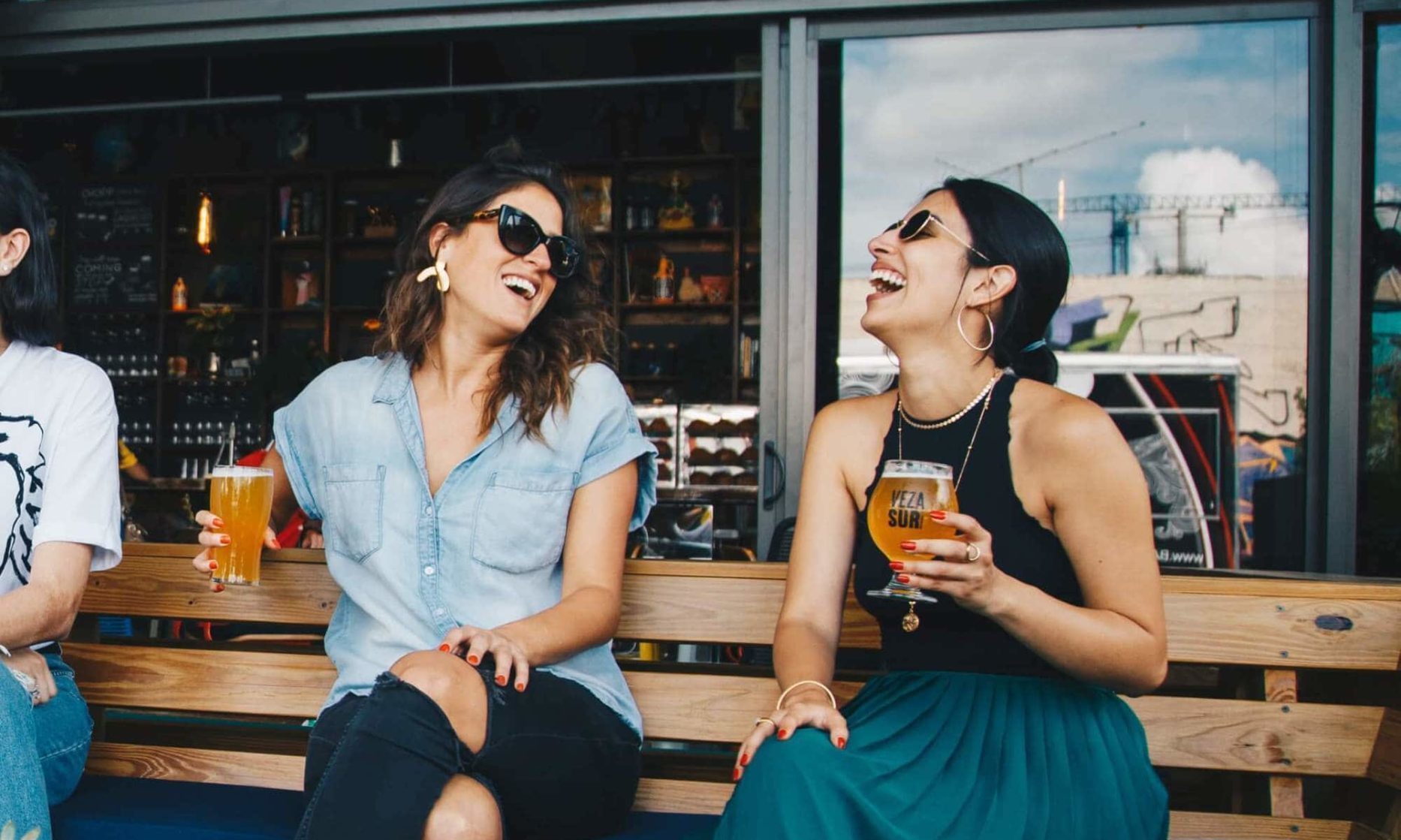 Two women laughing and drinking beer