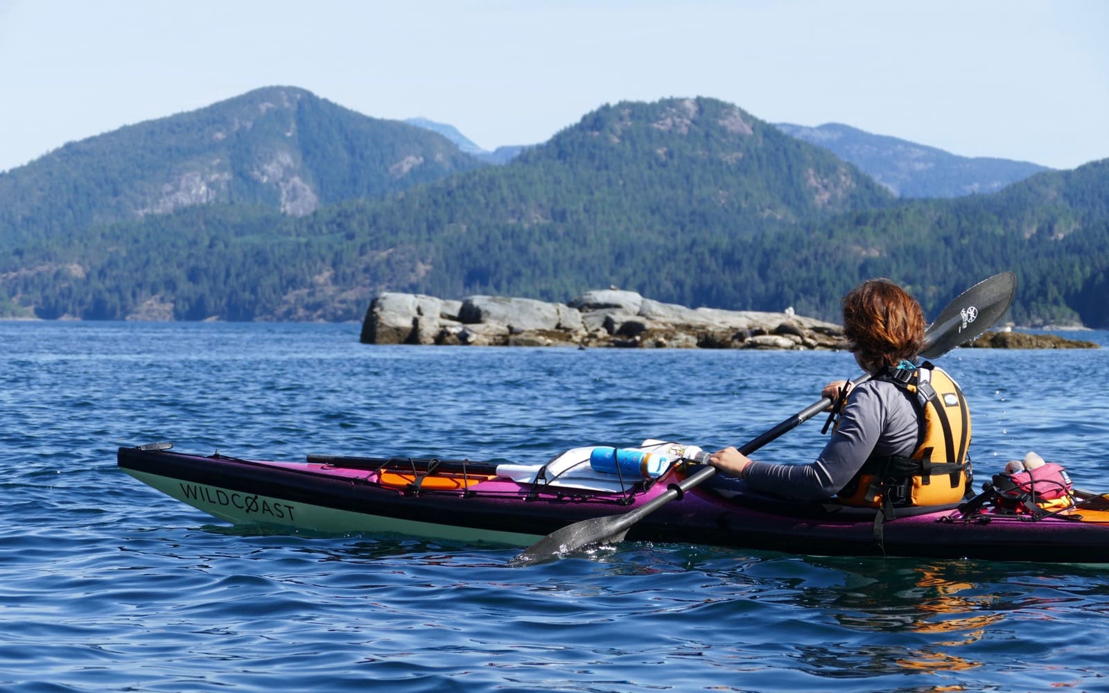 Kayaker looking at small reef in background