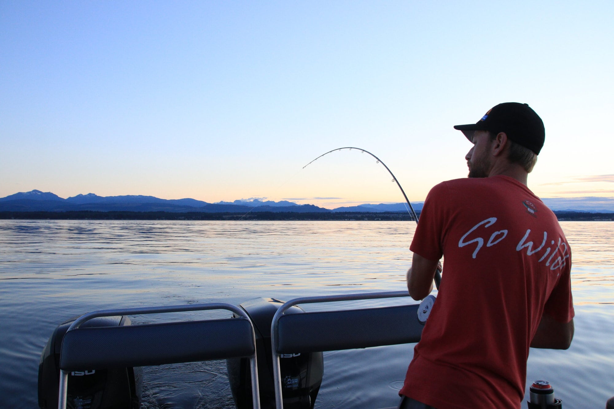 Person reeling in a fish at sunset