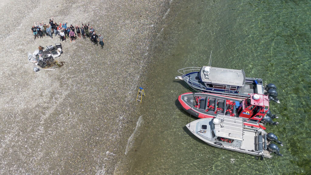 A group on Marina Island, next two pile of garbage collected, and three boats on shore