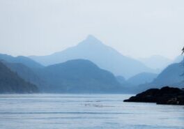 scenic image of ocean in the foreground and mountains in the background